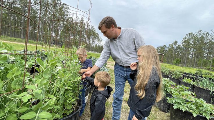 Travis Hammonds tends his garden with his children at their home in Alabama. Hammonds says donating their extra harvest to their local food bank helps fight food insecurity in their community and teaches his children the importance of giving back.